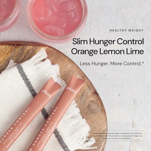 Slim Hunger Control drink packets with a pink beverage on a wooden tray.